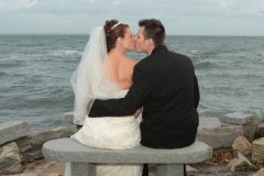 Groom kisses bride by sea